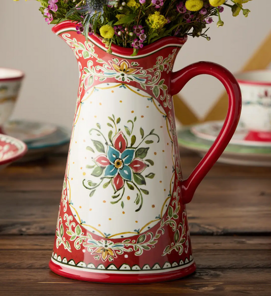 Decorative ceramic pitcher with floral design on a wooden surface