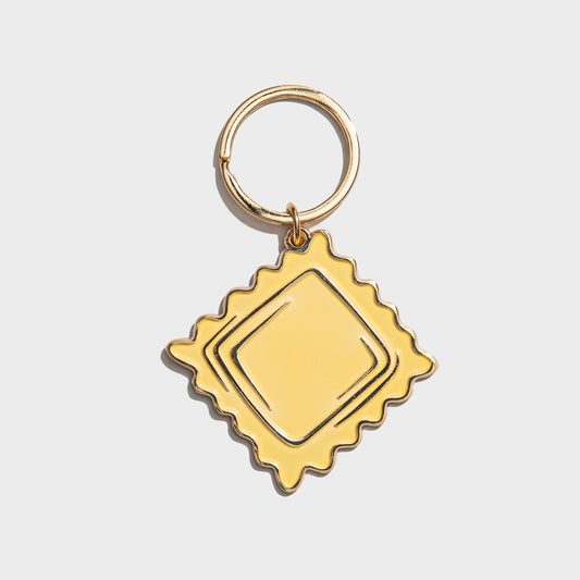 Gold Ravioli keychain with decorative frame on a light gray background