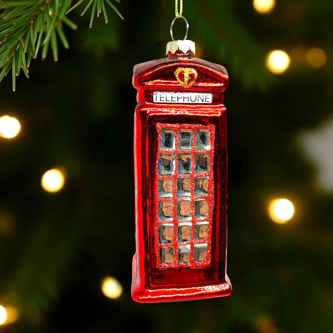 Red telephone booth ornament on a Christmas tree with blurred lights in the background