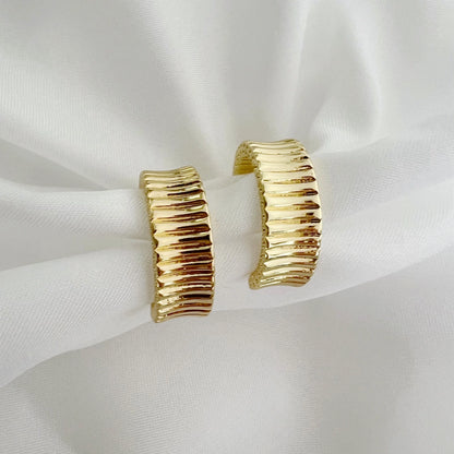 Gold hoop earrings on a white fabric background