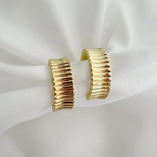 Gold hoop earrings on a white fabric background