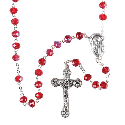 Red beaded rosary with silver cross and Our Lady of Lourdes medal on a white background