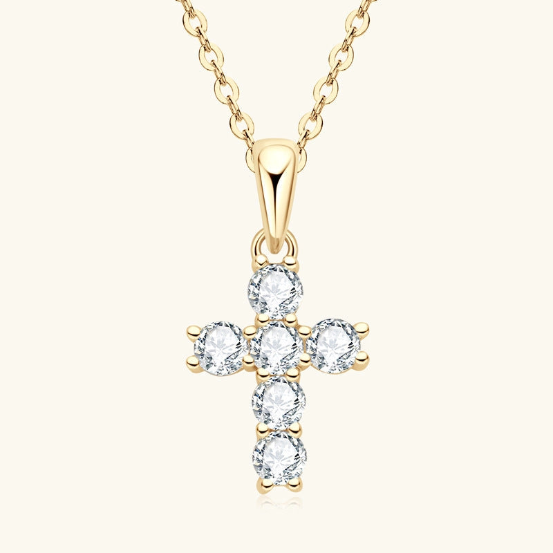 Gold cross-shaped pendant with clear stones on a white background
