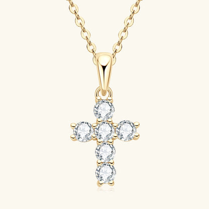 Gold cross-shaped pendant with clear stones on a white background
