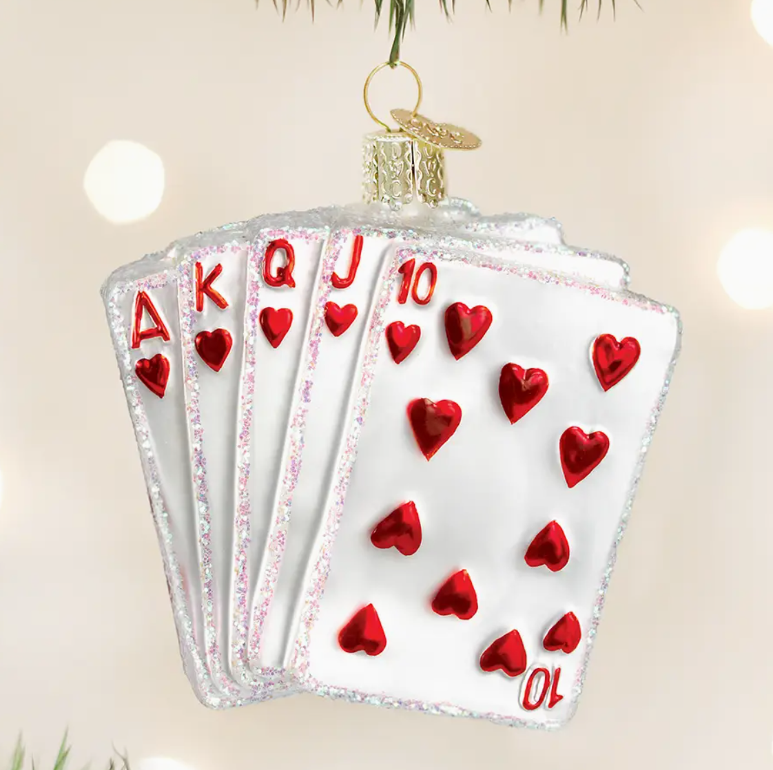 Decorative ornament shaped like a fan of playing cards with red hearts on a beige background.