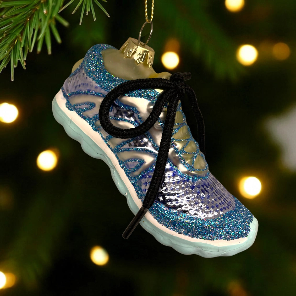 Blue and silver glittery sneaker ornament on a Christmas tree with lights in the background