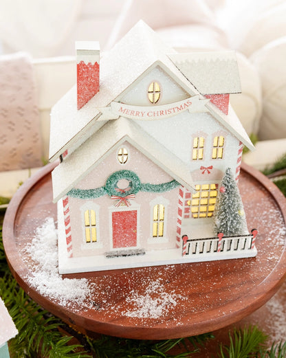 Decorative Christmas house on a wooden stand with a snowy effect