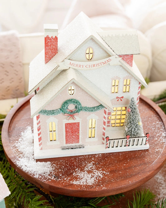 Decorative Christmas house on a wooden stand with a snowy effect