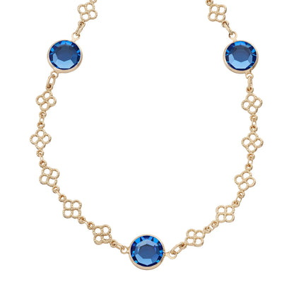 A gold-tone chain necklace featuring three round-cut blue faceted gemstones set in gold bezels, displayed on a clean white background.