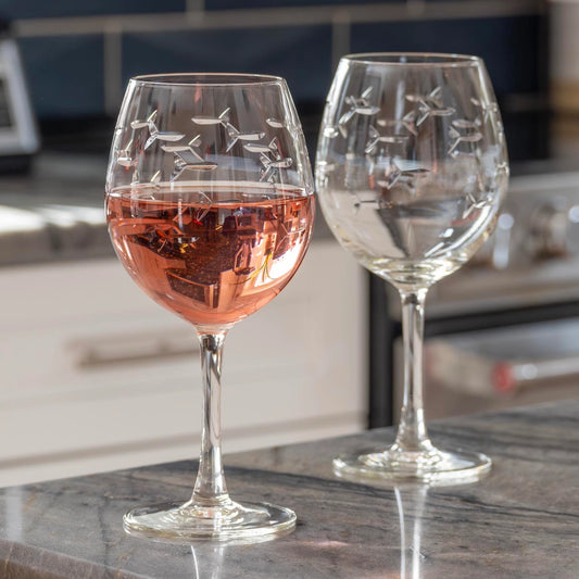 Two wine glasses with airplane etching on a kitchen counter.