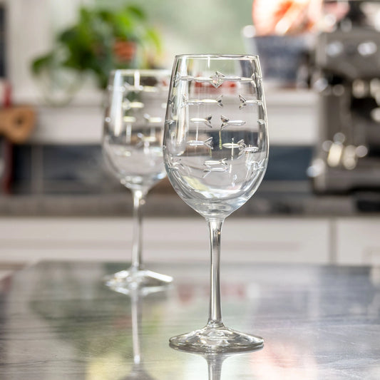 Two clear wine glasses with engraved designs on a kitchen counter.