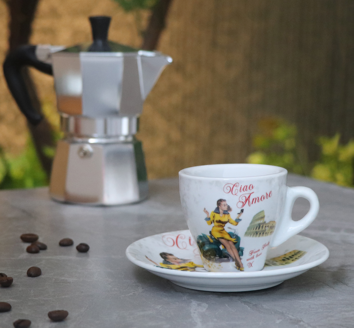 Espresso cup and saucer with a Moka pot on a table outdoors.