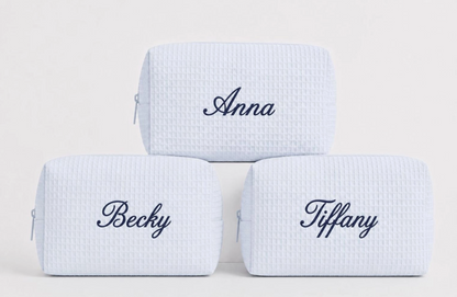 Personalized light blue waffle makeup bags with custom names embroidered in navy thread