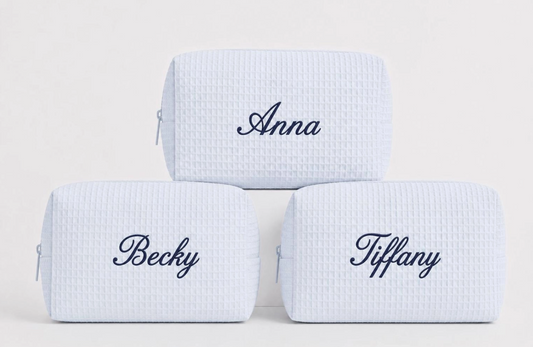 Personalized light blue waffle makeup bags with custom names embroidered in navy thread