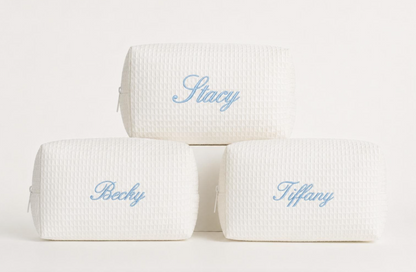 Personalized cream waffle cosmetic bags with embroidered names in light blue thread
