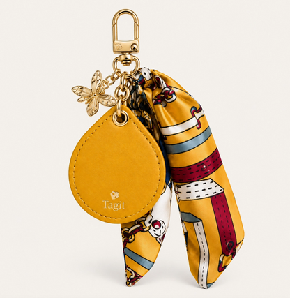 Mustard yellow vegan leather AirTag bag charm with colorful scarf, gold-plated bee-inspired charms and clip