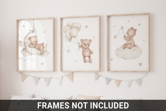 Set of three watercolor teddy bear nursery wall art prints featuring a bear on a crescent moon, a bear holding balloons, and a bear sitting on a cloud with stars, displayed in wooden frames above a nursery bed.