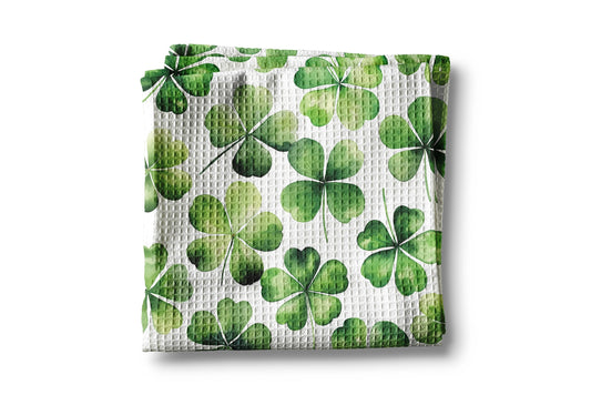 Waffle-textured kitchen towel with green four-leaf clover pattern on a white background