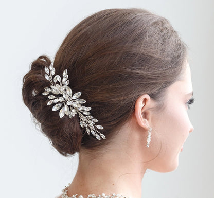 Woman with elegant hair bun adorned with a decorative hairpiece against a plain background