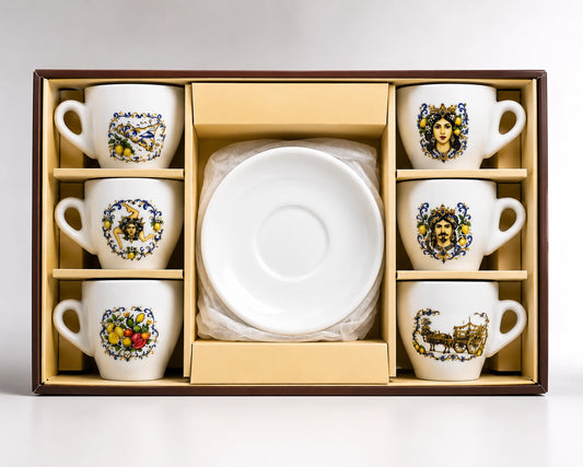 A boxed ceramic tea or coffee cup and saucer set displayed in an open presentation box. The set includes six white cups with colorful illustrated floral and portrait designs, six matching saucers, and a stack of clear plastic-wrapped plates or napkins in the center, all set against a light gray background.