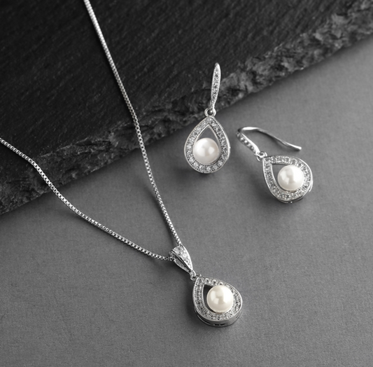 Silver jewelry set with pearl accents on a dark surface