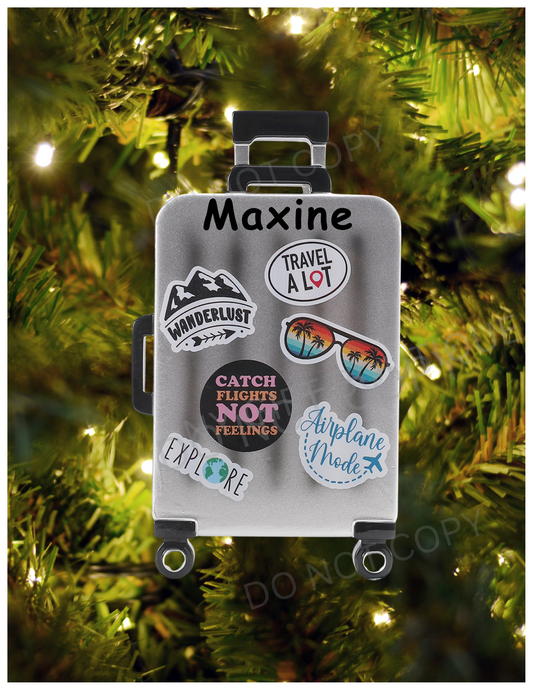 Decorative suitcase ornament with travel-themed stickers on a Christmas tree.