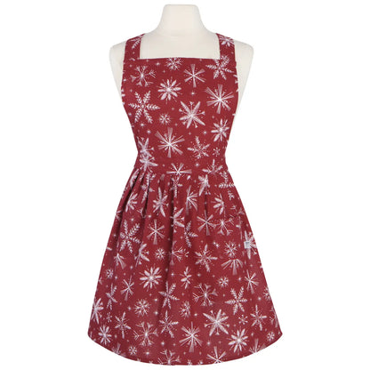 A sleeveless red apron dress with a white snowflake pattern, displayed on a cream mannequin torso against a plain white background.