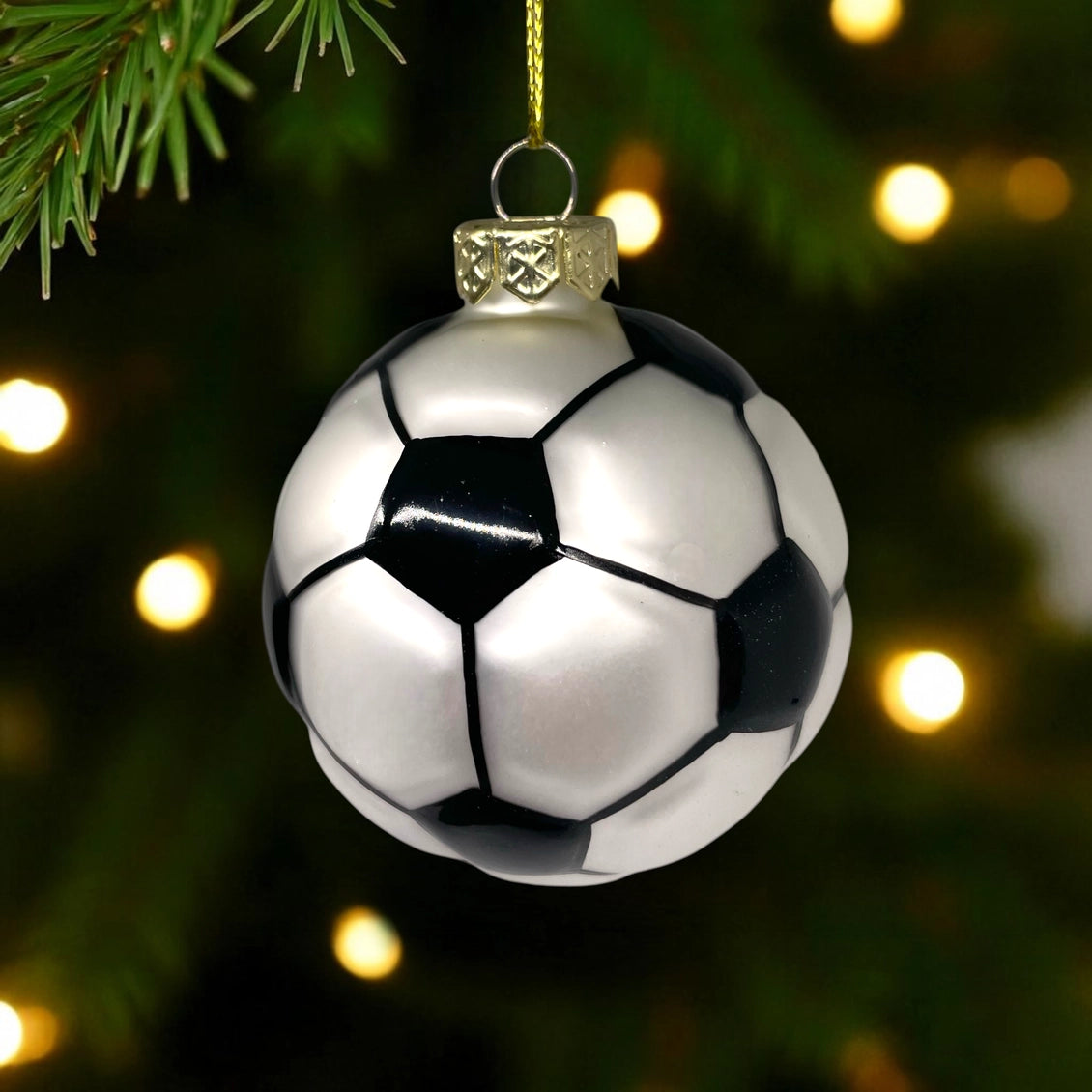 Soccer ball Christmas ornament hanging on a tree with lights in the background