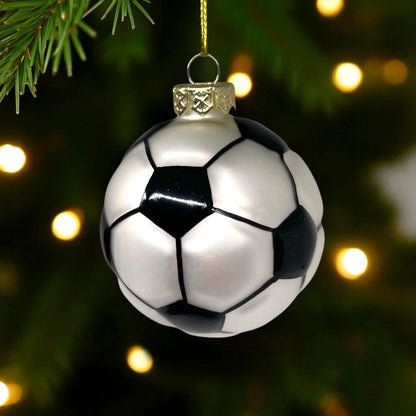 Soccer ball Christmas ornament hanging on a tree with lights in the background