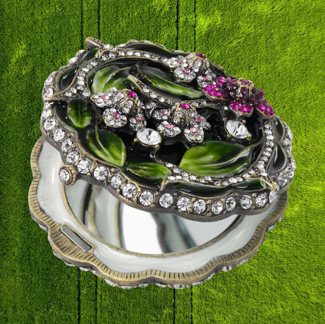 Decorative jewelry box with floral design and gemstones on a green wooden surface