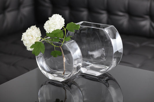 Clear spherical glass vase with white flowers on a reflective surface