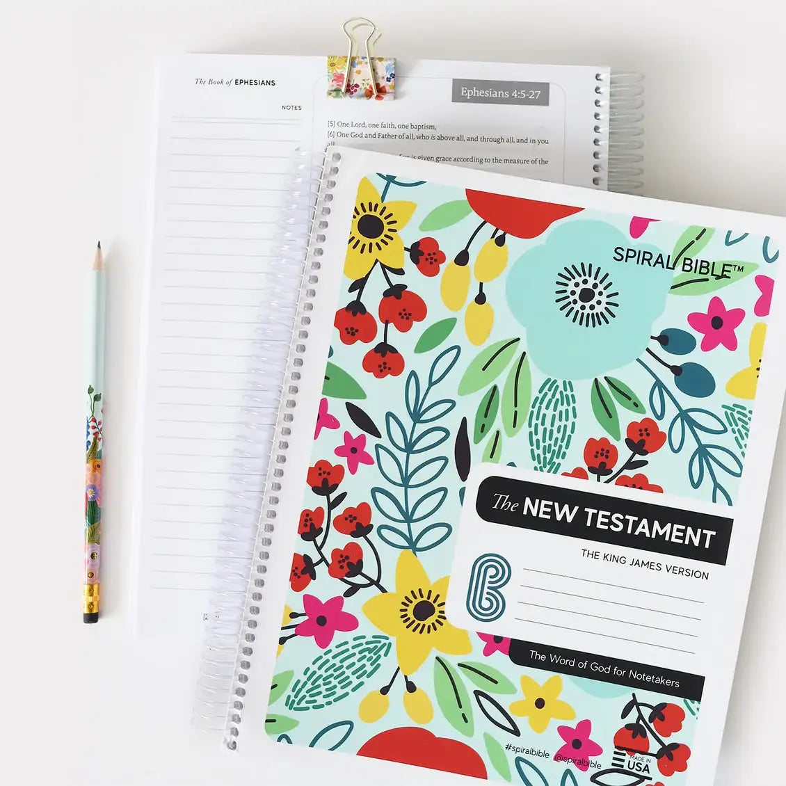 Spiral-bound Bible with colorful floral design on a white background