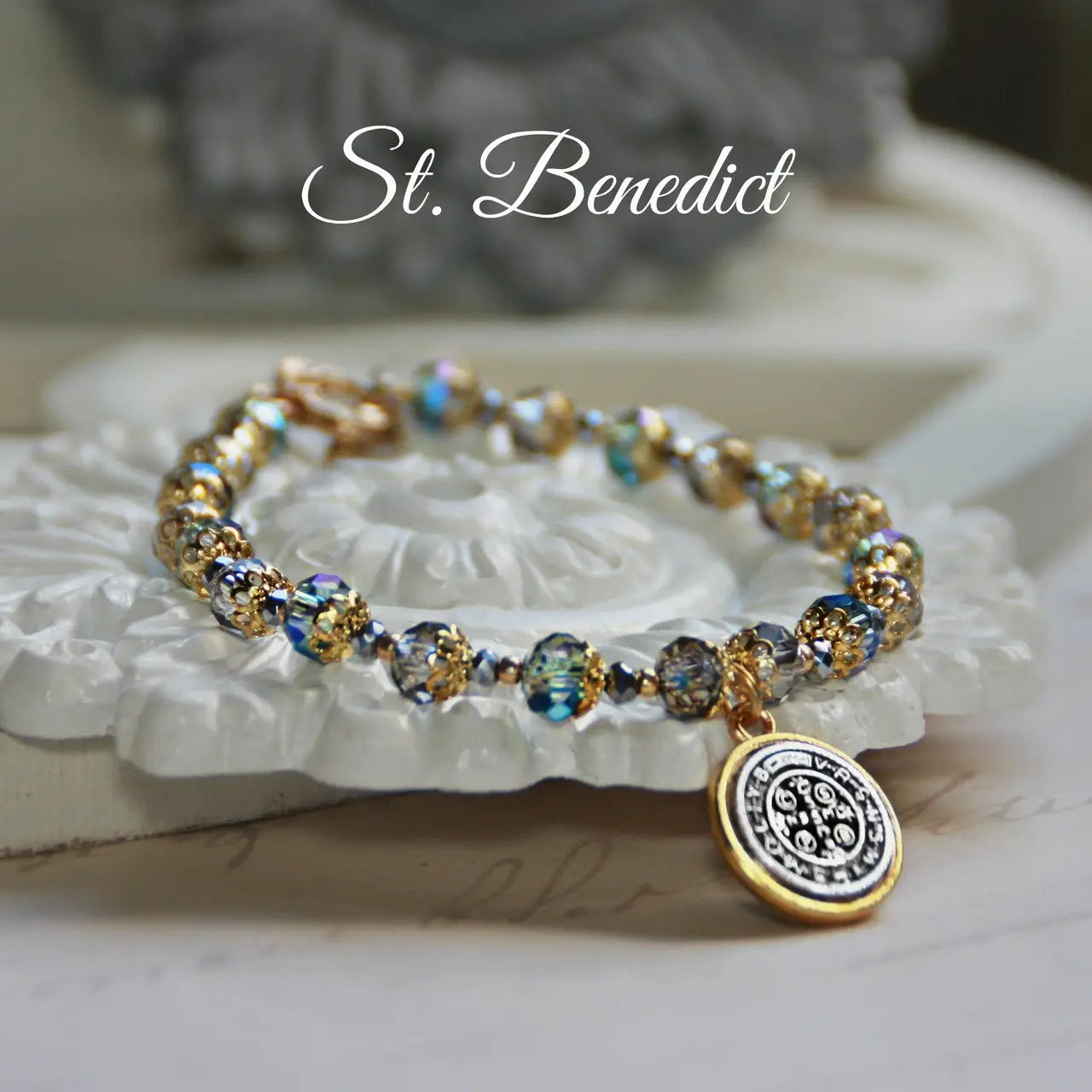 Bracelet with beads and a charm on a decorative surface, featuring 'St. Benedict' text.