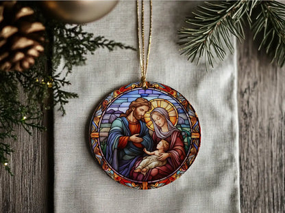 Decorative Christmas ornament with stained glass design of a family, surrounded by pine branches and pinecones.
