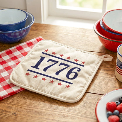 Potholder with '1776' design on a wooden table with kitchen items.
