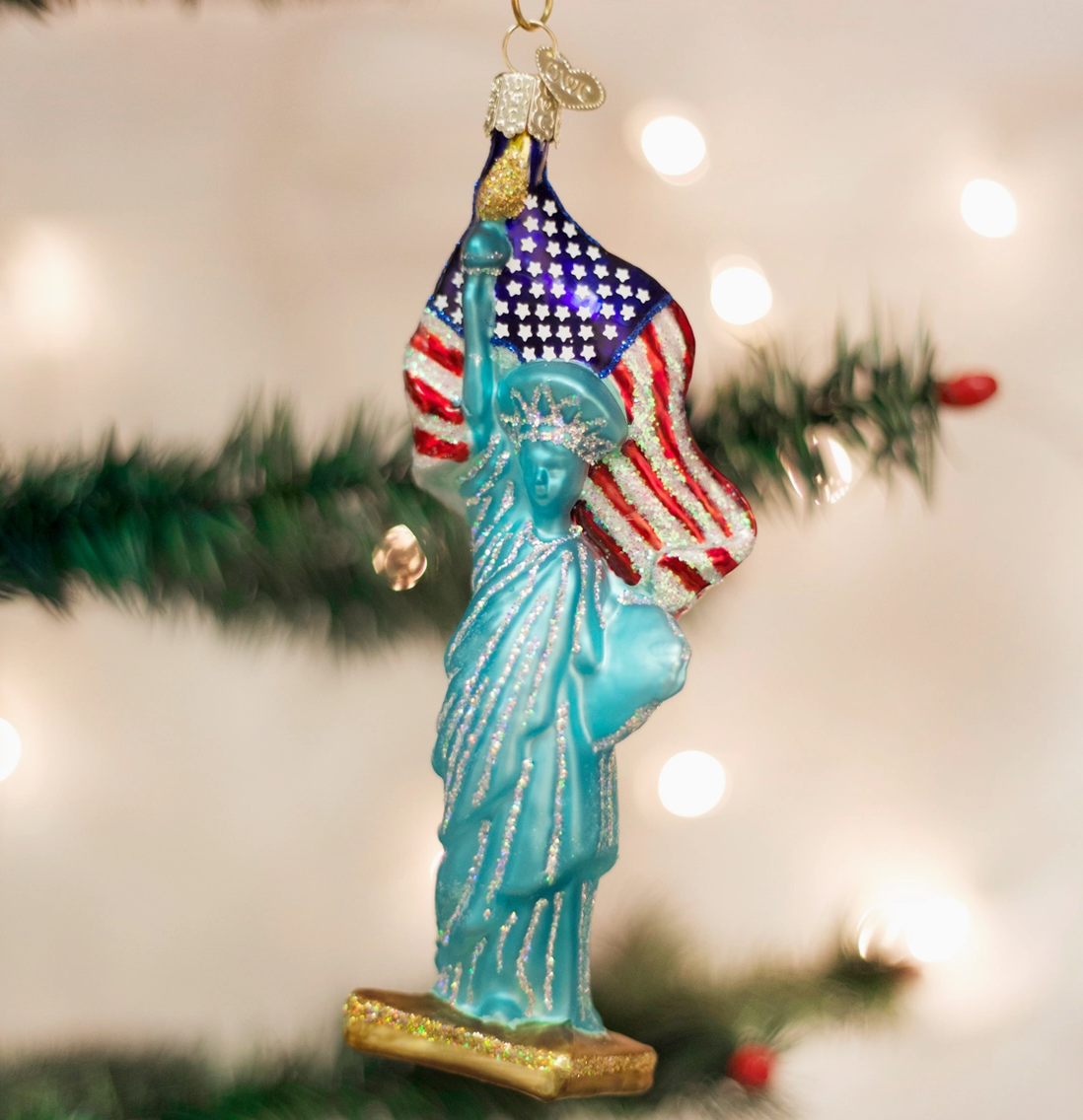 Statue of Liberty ornament with American flag against a blurred Christmas tree background