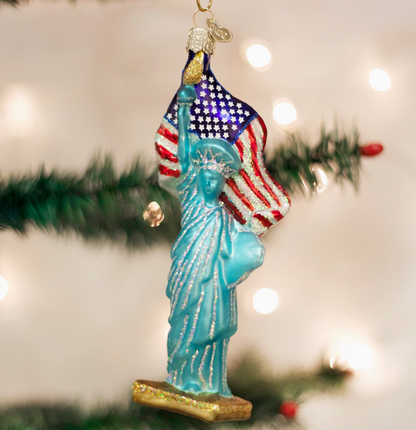 Statue of Liberty ornament with American flag against a blurred Christmas tree background