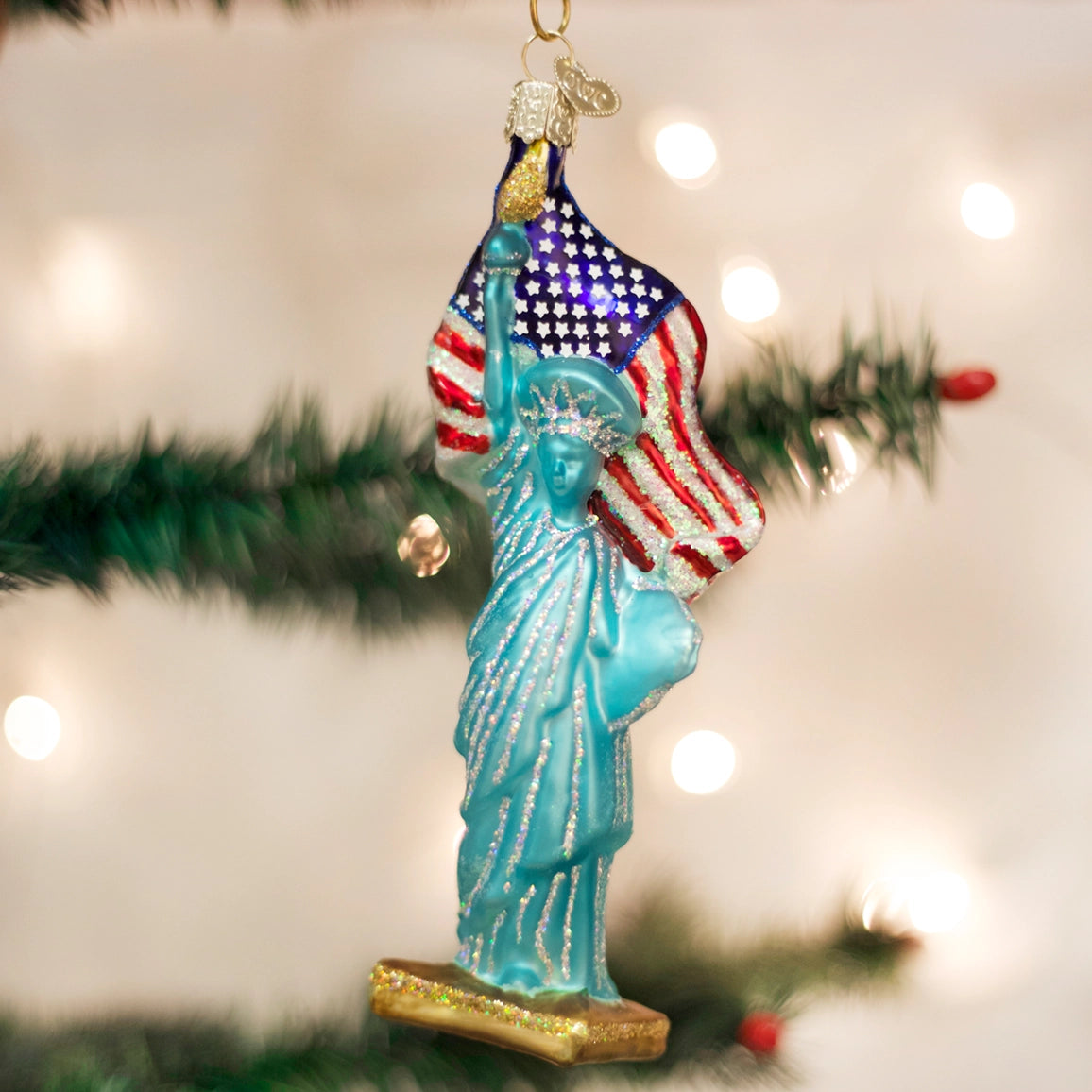 Statue of Liberty ornament with American flag against a Christmas tree background
