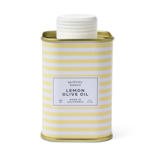 A metal tin of McEvoy Ranch Lemon Olive Oil with a white screw cap, featuring a yellow and white striped pattern and a white label on a clean white background.