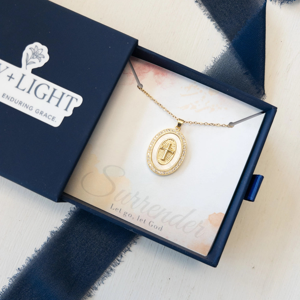 Gold Cross necklace in a box on a textured surface