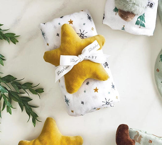 Two yellow star-shaped toys and a plush moose toy on a white surface with greenery.