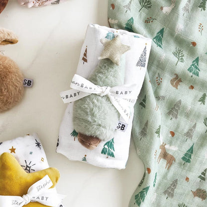 Baby swaddle with forest pattern and matching blanket on a white surface