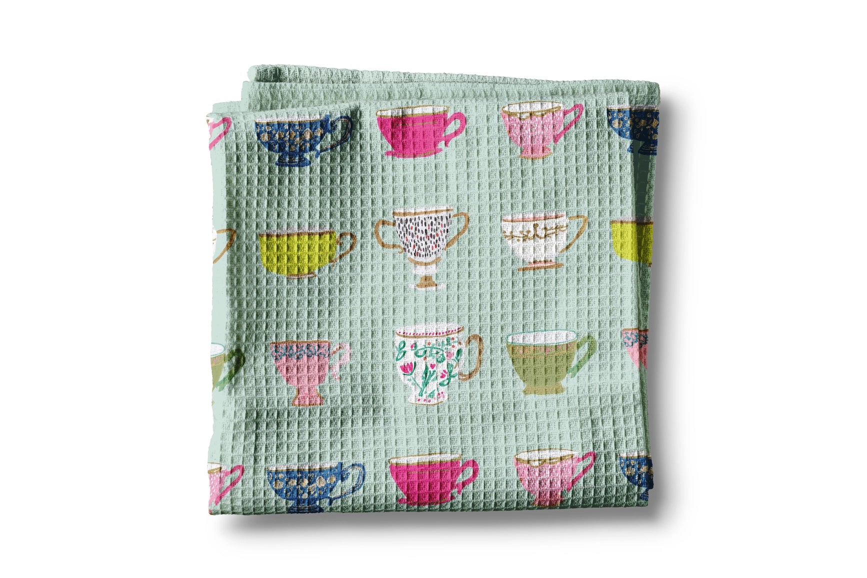 Folded green fabric with colorful teacup pattern on a white background