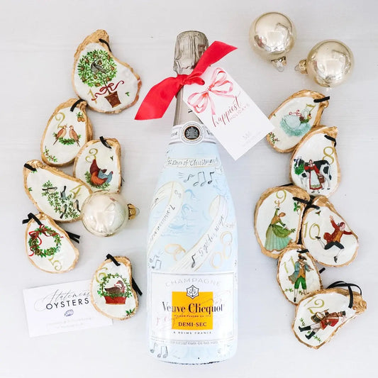Bottle of Veuve Clicquot surrounded by decorative oyster shells on a white background