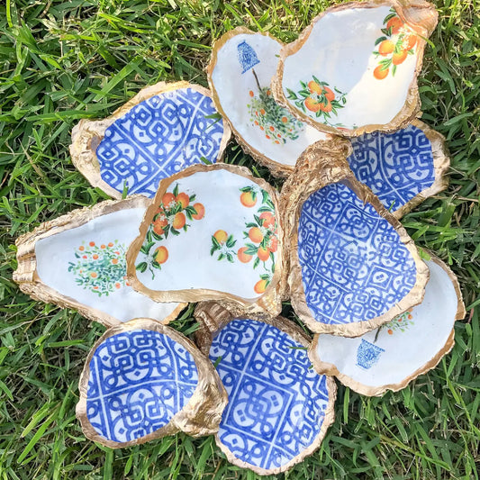 Decorative oyster shells with blue and white patterns and orange designs on a grass background
