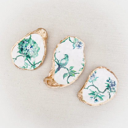 Decorative oyster shells with floral, chinoiserie and bird patterns on a light background