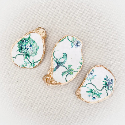 Decorative oyster shells with floral, chinoiserie and bird patterns on a light background