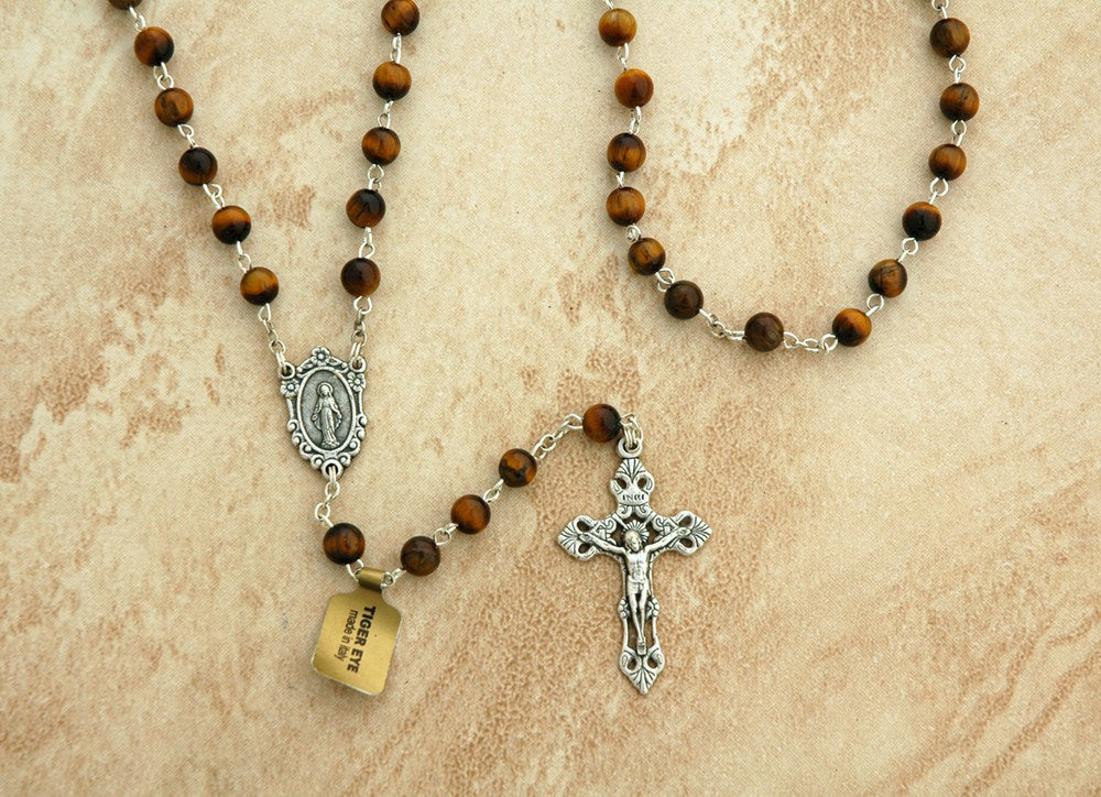 Wooden rosary beads with silver crucifix and medal on a beige background