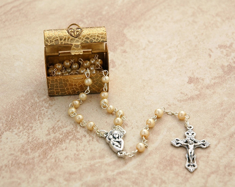 Rosary with pearl beads and silver crucifix on a textured surface