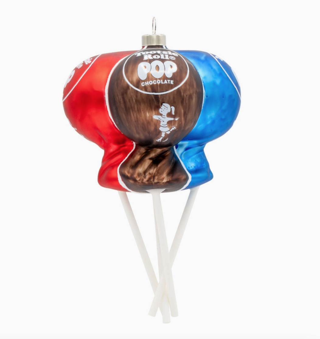 A novelty Christmas ornament shaped like a lollipop, featuring a red and blue candy-coated shell with a brown chocolate center and white hanging sticks, on a plain white background.